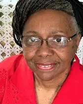 A woman in red shirt and glasses smiling.